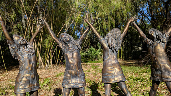Bronze Statues Featuring Four Women with Their Hands in the Air